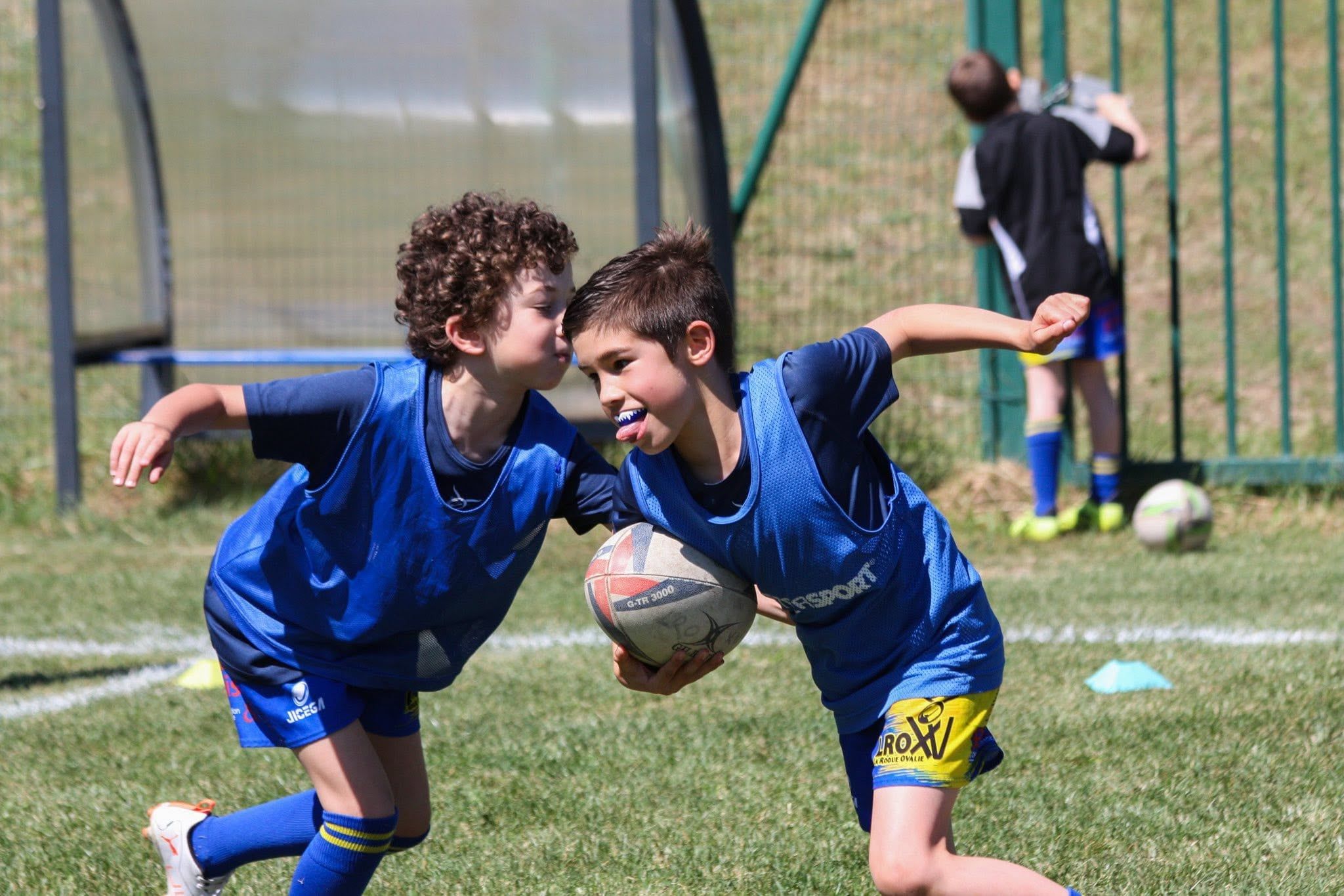 Deux jeunes de l'école de rugby courent ballon en main pendant un entraînement