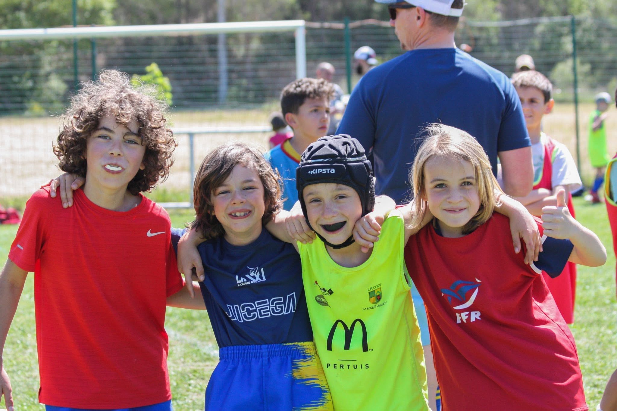 Quatre jeunes joueurs souriants au bord du terrain